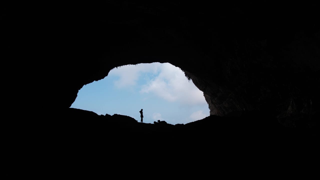 Silhouette of a person at a cave mouth